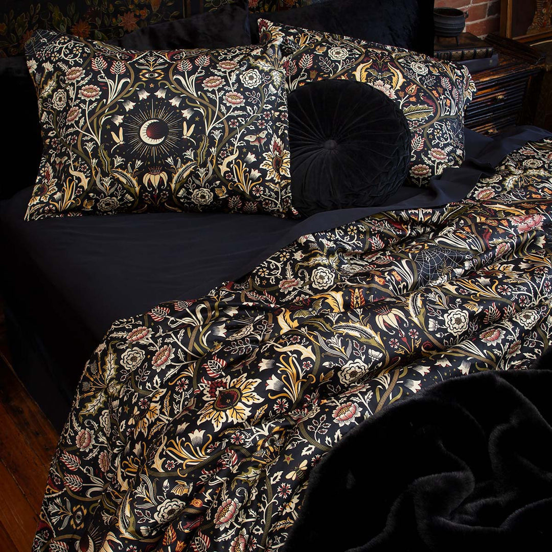 Night Garden in Harvest colorway on a bed with black bamboo bedding. Botanicals in burgundy & moss