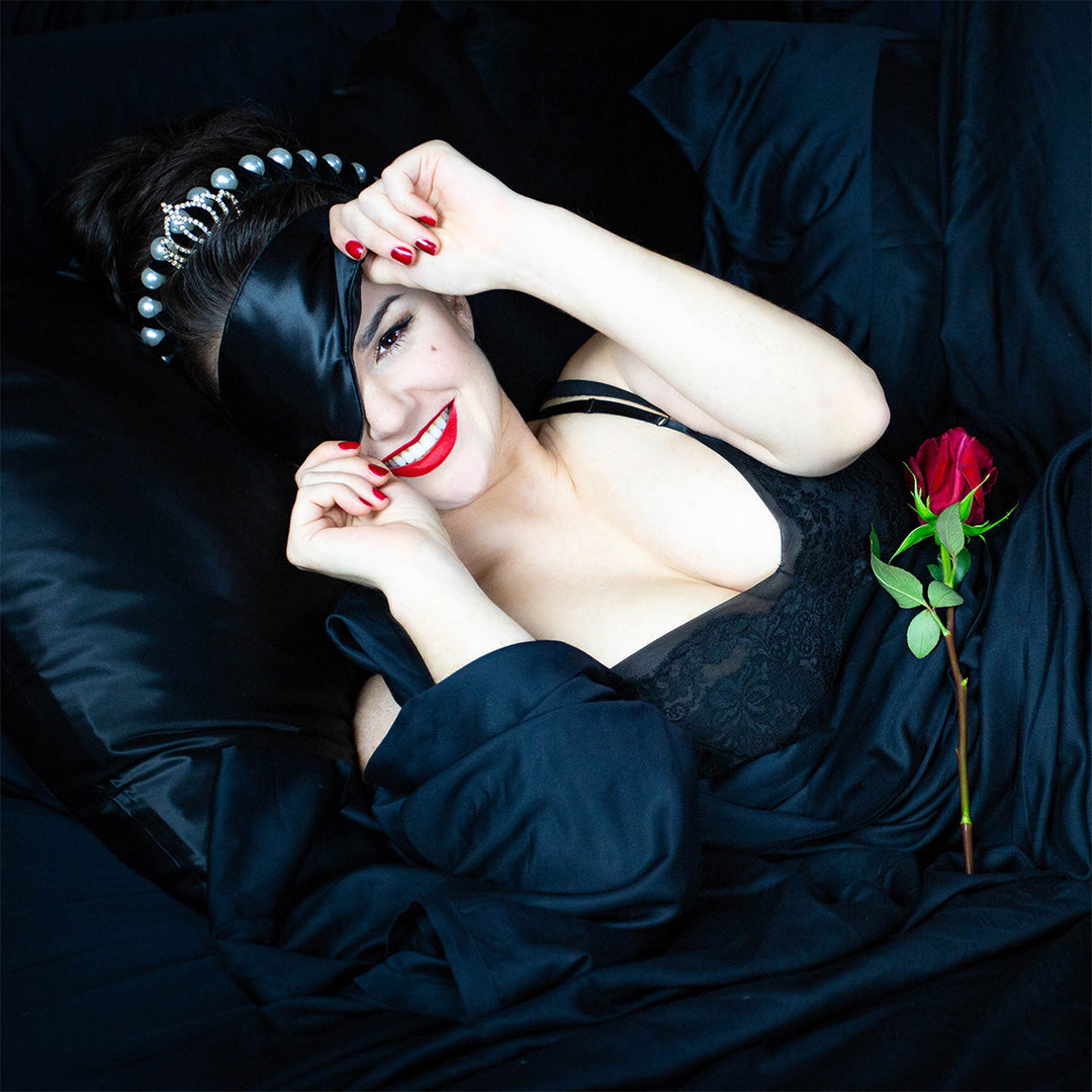 Woman laying on a silk pillowcase with a silk eyemask