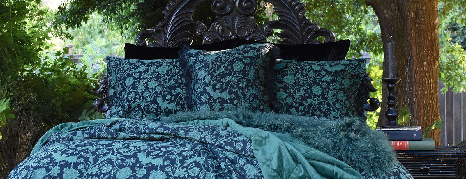 Sin in Linen's Elysian Fields pattern in green on a bed outdoors. Shop Gothic Botanical bedding & decor for your whimsical home.