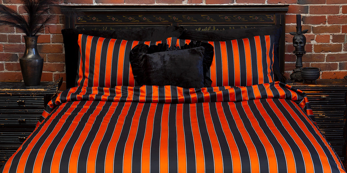 Pumpkin orange and black striped bedding on a bed for a circus inspired bedding look. 