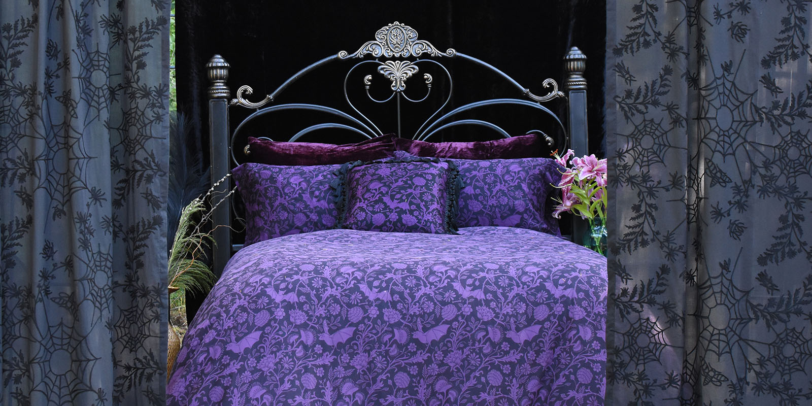 Sin in Linen's Elysian Fields pattern in purple on a bed outdoors. Shop Gothic Botanical bedding & decor for your whimsical home.