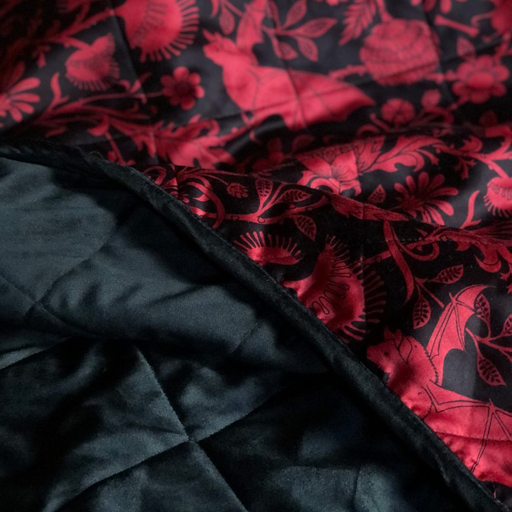 Close-up view of a black velvet blanket with red Elysian Fields bat print.
