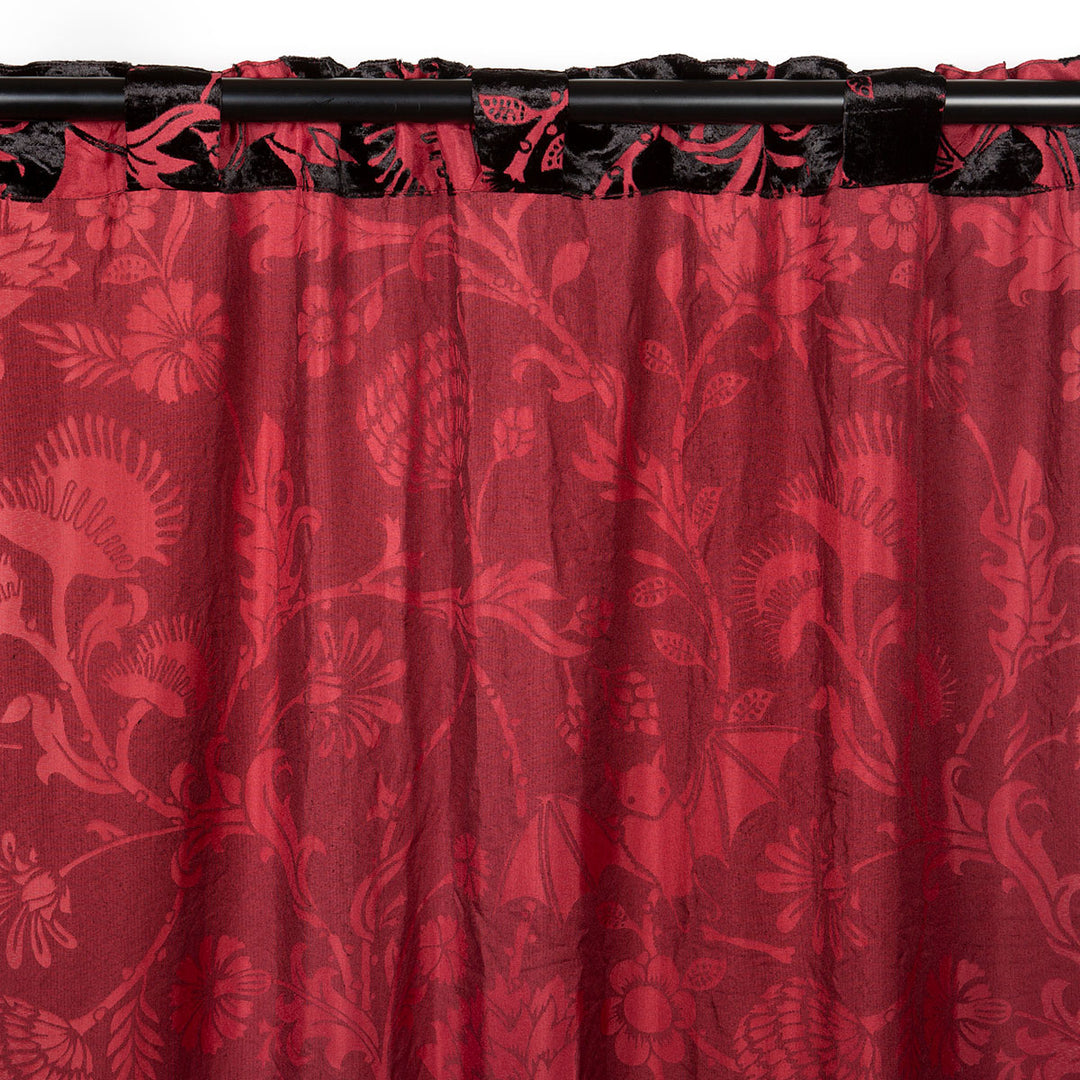 Burgundy red and black velvet curtain with a gothic botanical pattern featuring bats and venus fly traps. 