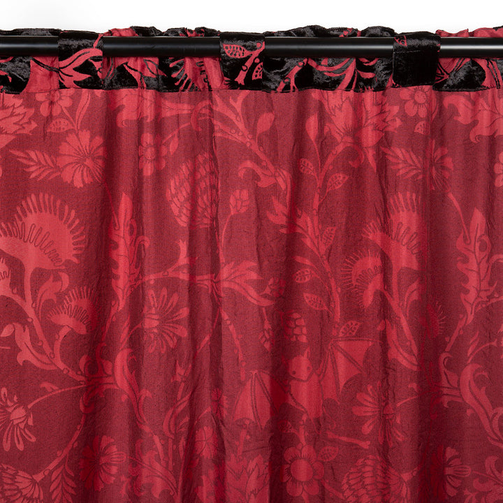 Burgundy red and black velvet curtain with a gothic botanical pattern featuring bats and venus fly traps. 
