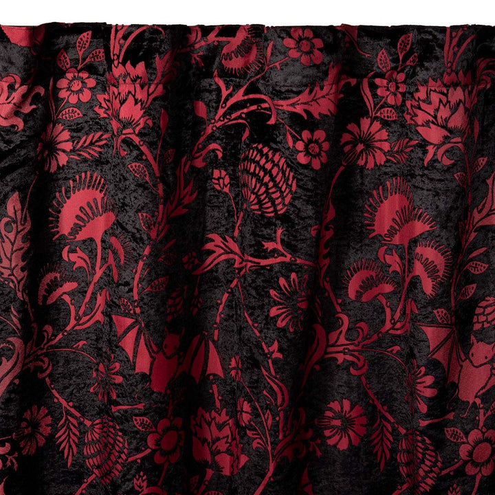 Burgundy red and black velvet curtain with a gothic botanical pattern featuring bats and venus fly traps. 