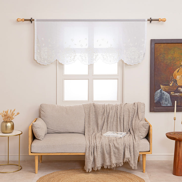 Ivory cotton window valance with ivory spider web cottagecore and whimsigoth embroidery. The window valance is hung on a curtain rod above a couch in a living room.