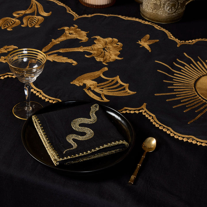 Bronze Embroidered Table Runner featuring motifs from Sin in Linen's Night Garden pattern. Make a dark, witchy table with this centerpiece. Also featured is the gold Embroidered Snake Sapkin. 