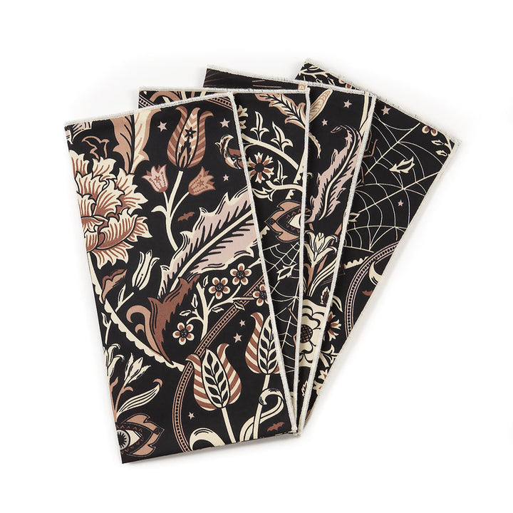 Set of four black botanical patterned napkins on a white background