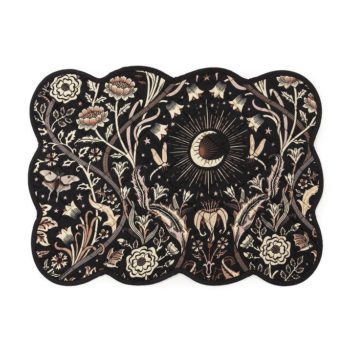 A dark floral quilted placemat with scalloped edges and a black background
