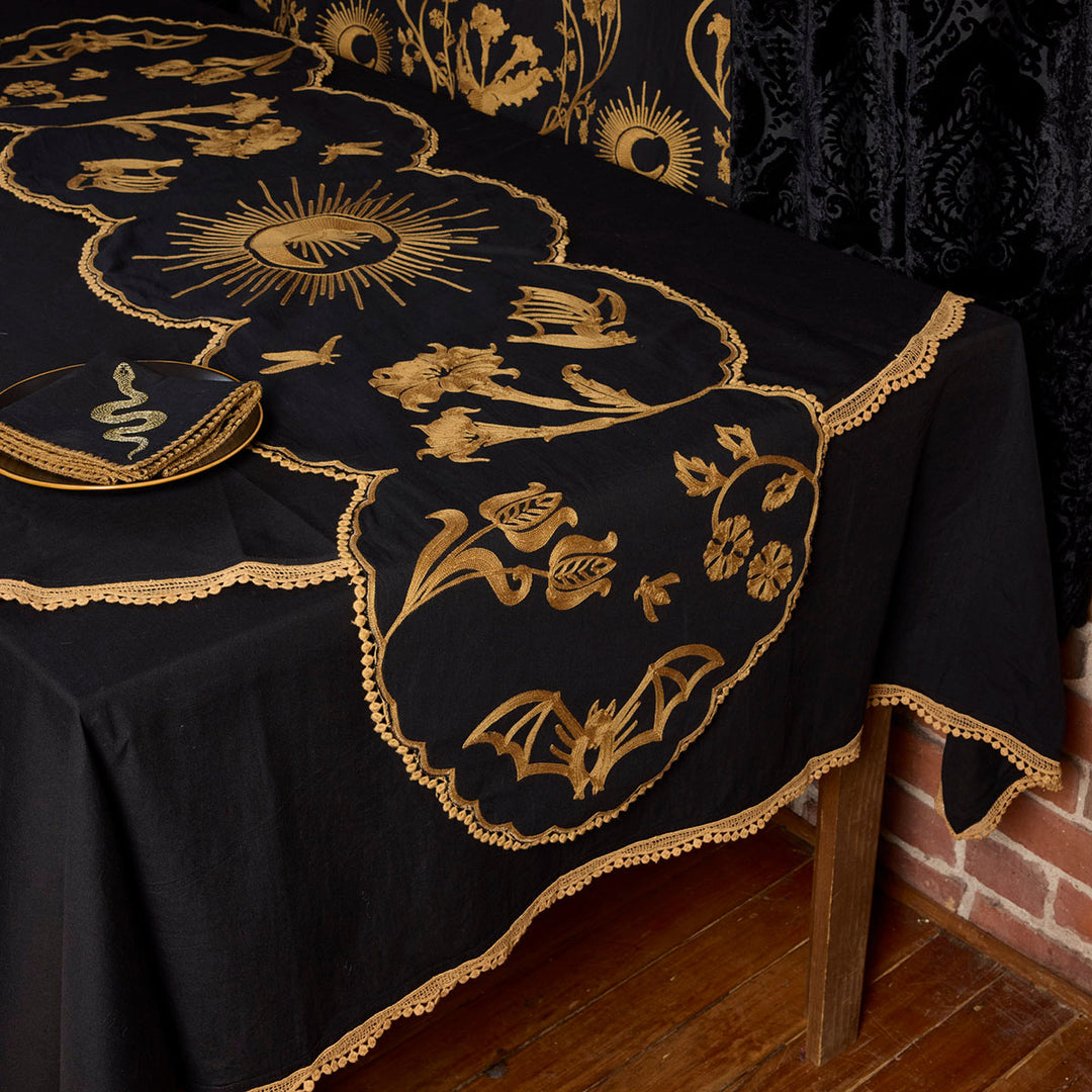 Bronze Embroidered Table Runner featuring motifs from Sin in Linen's Night Garden pattern. Make a dark, witchy table with this centerpiece. 