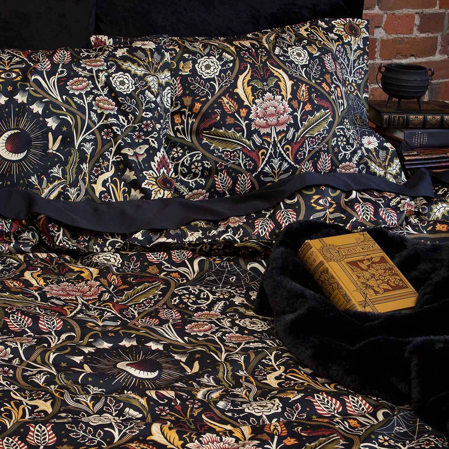 Night Garden Harvest botanical bedding on a bed. Features florals, serpents, and spiders for a nature inspired bedroom. 