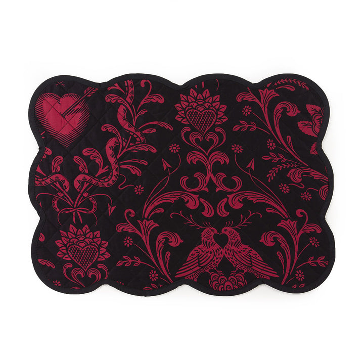 A deep blush on black quilted placemat with scalloped edges