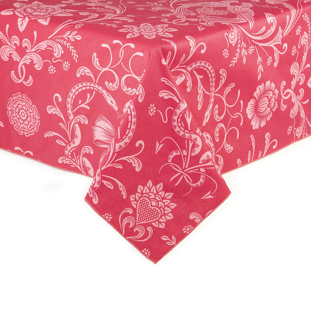 A pink on pink tablecloth featuring serpents, hearts, and flowers