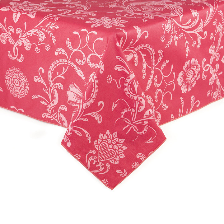 A pink on pink tablecloth featuring serpents, hearts, and flowers