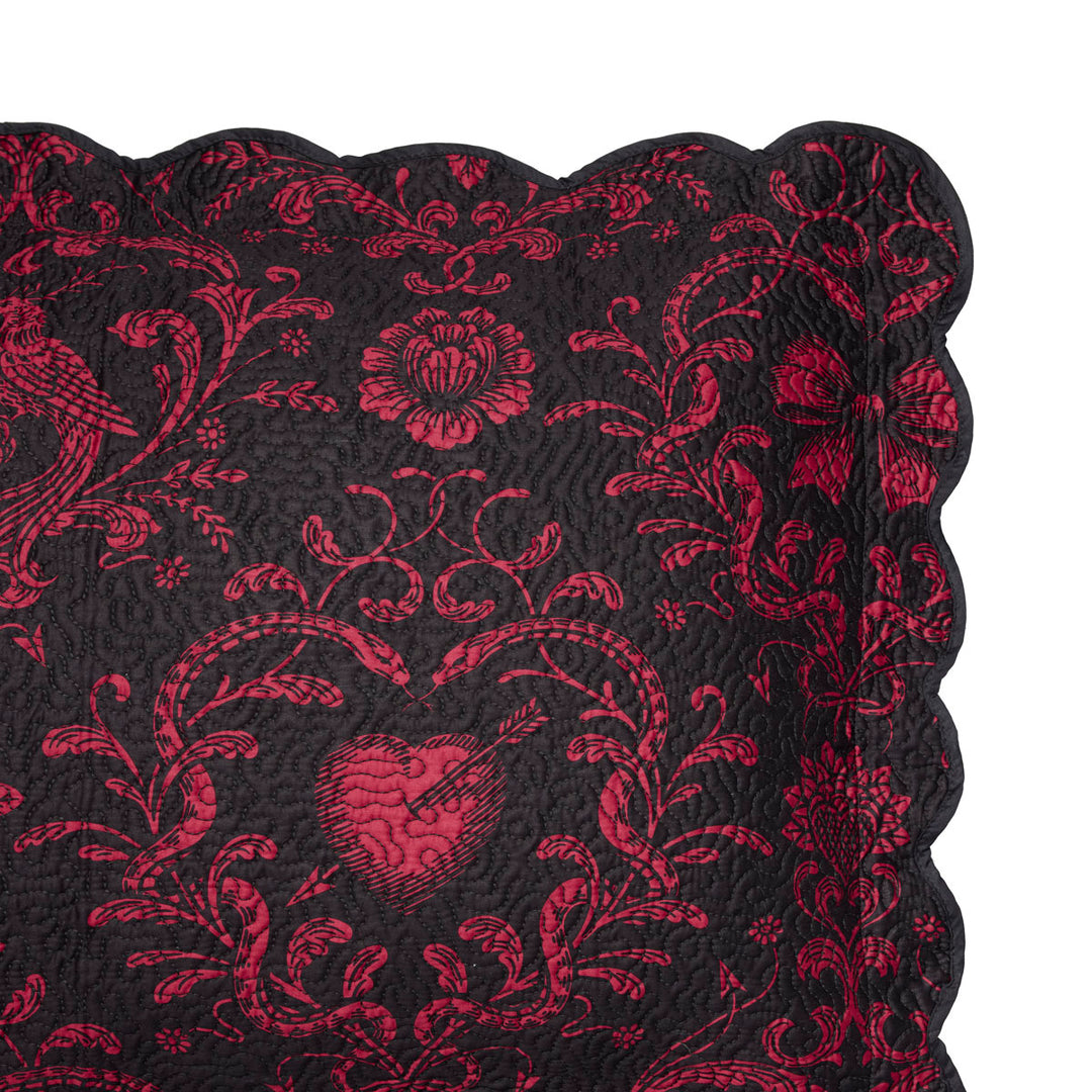 Quilted sham featuring pierced hearts, serpents, and bows in pink and black. 