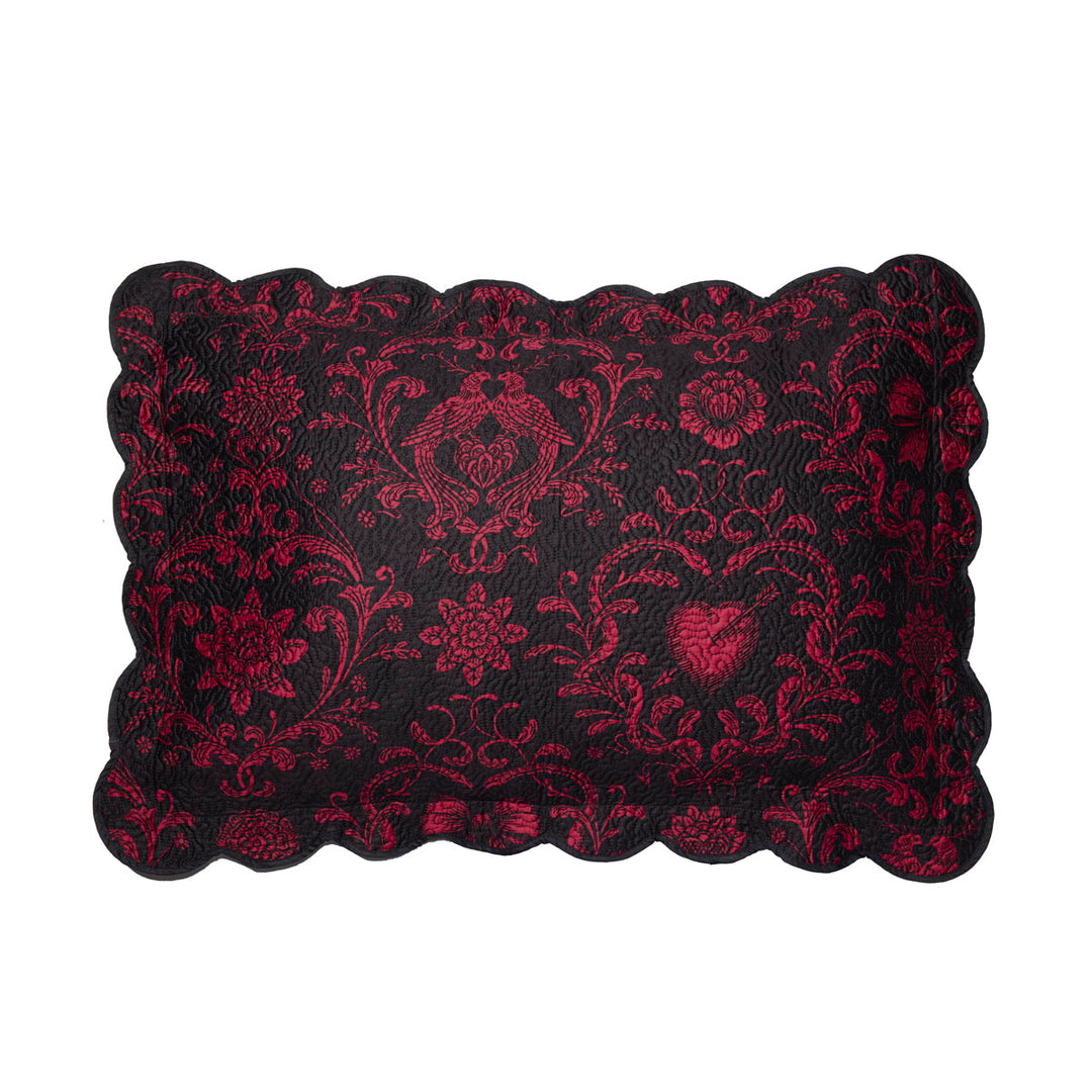 Quilted sham featuring pierced hearts, serpents, and bows in pink and black. 