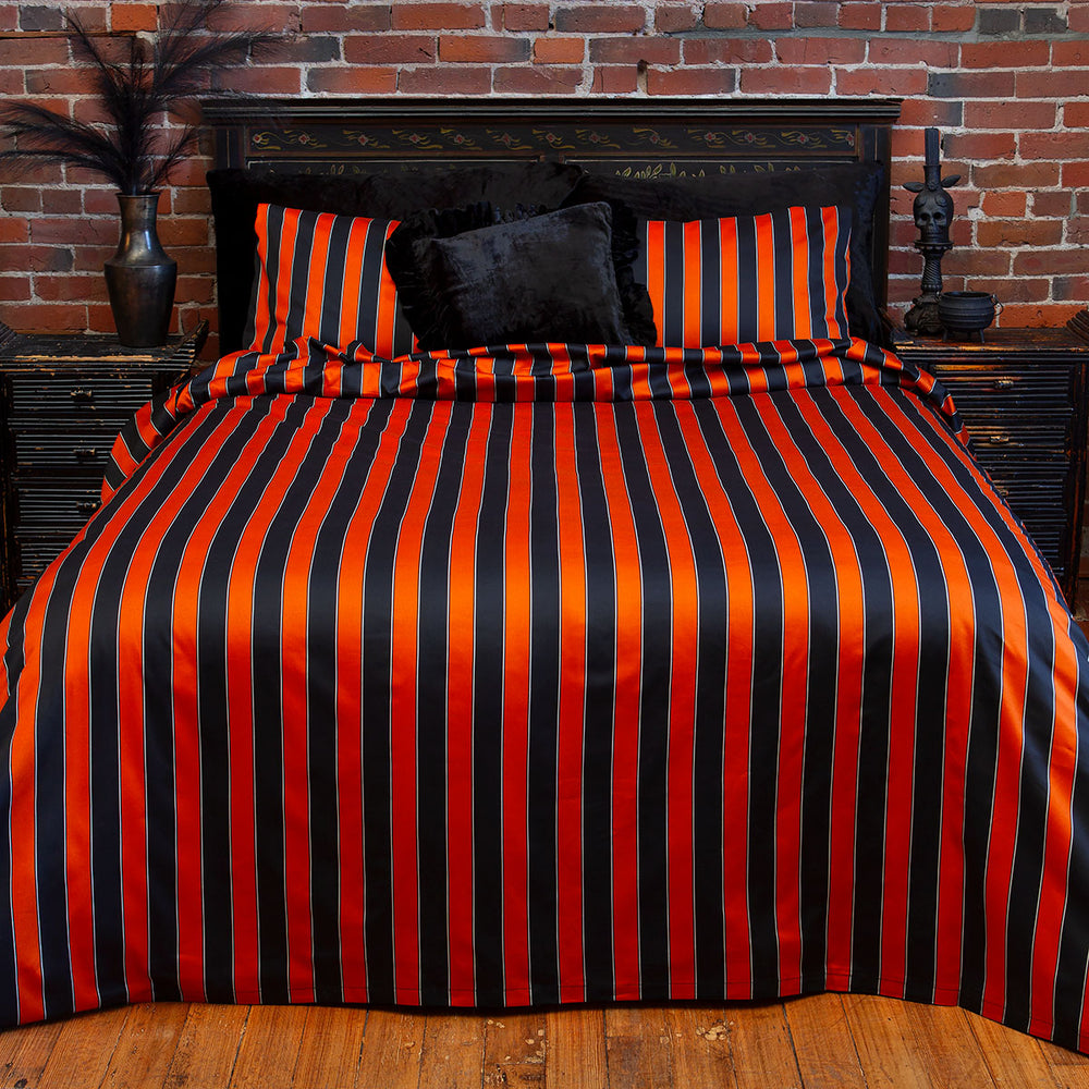 Pumpkin orange and black striped bedding on a bed. Inspired by vintage circus, gothic style for a Halloween all year round look. 