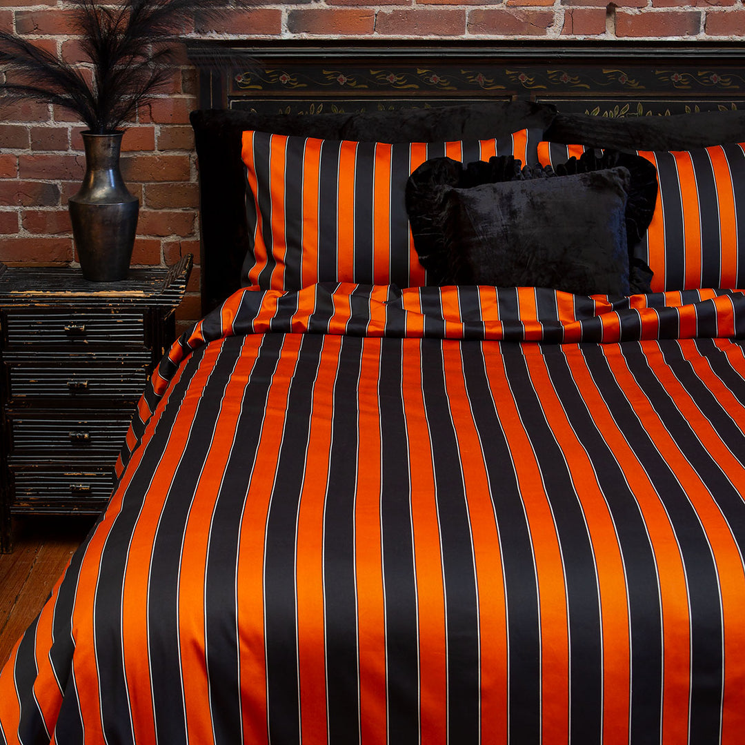 Pumpkin orange and black striped bedding on a bed. Inspired by vintage circus style for a Halloween all year round look. 