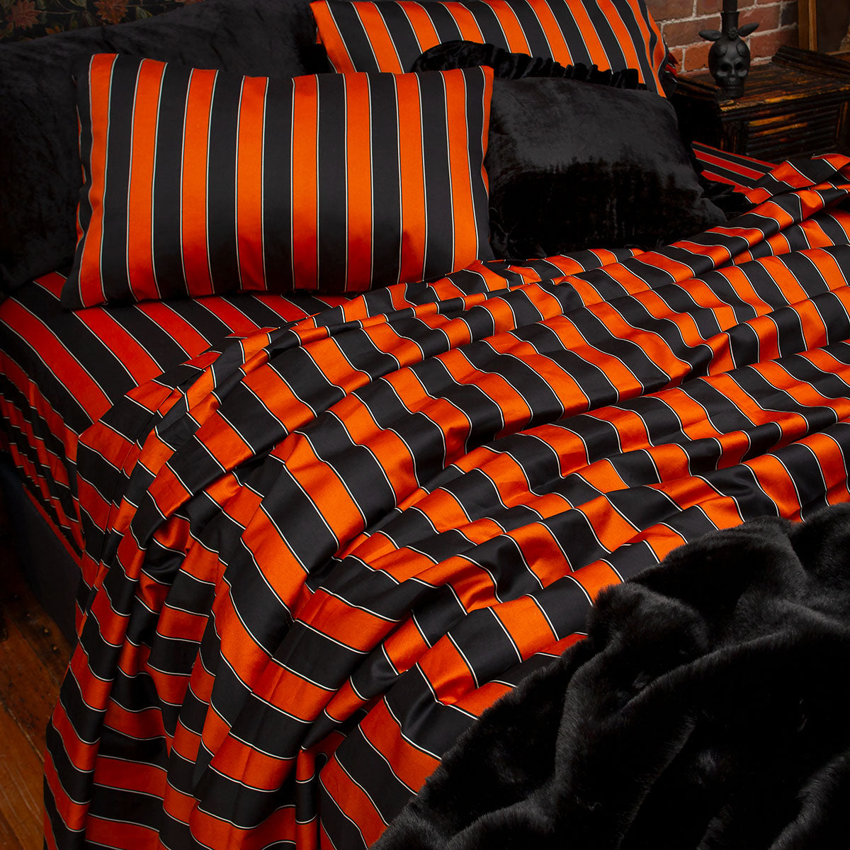 Pumpkin orange and black striped bedding on a bed. Inspired by vintage circus, gothic style for a Halloween all year round look. 