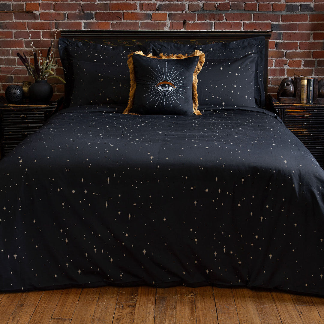 Celestial and night sky inspired bedding featuring bronze stars by Sin in Linen. On the bed is a coordinating bed set.