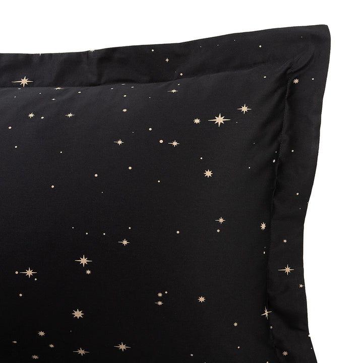 Corner of a pillow sham with a bronze star print. Celestial and bohemian bedding by in in Linen. 