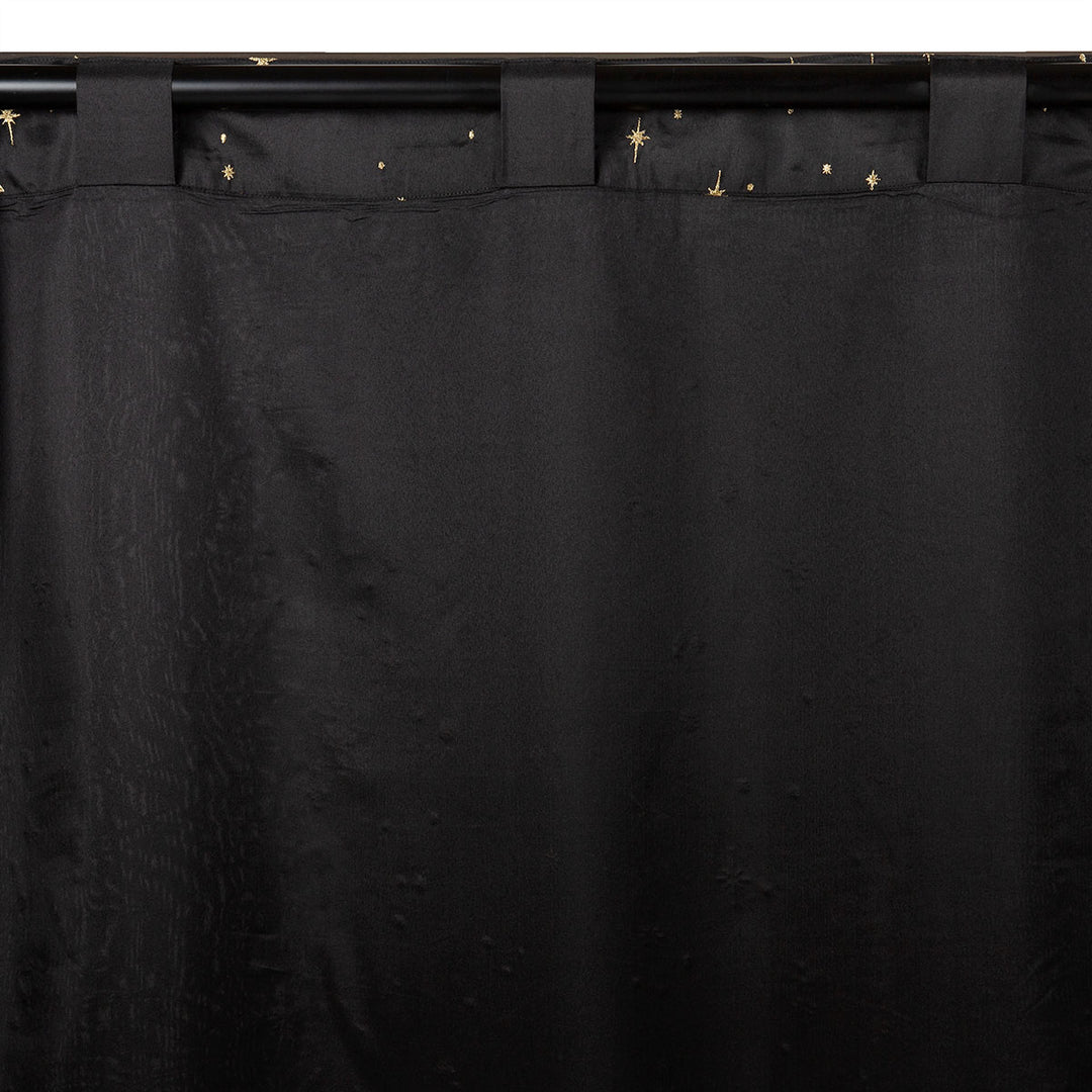 Back of a black semi-sheer curtain with embroidered gold star pattern