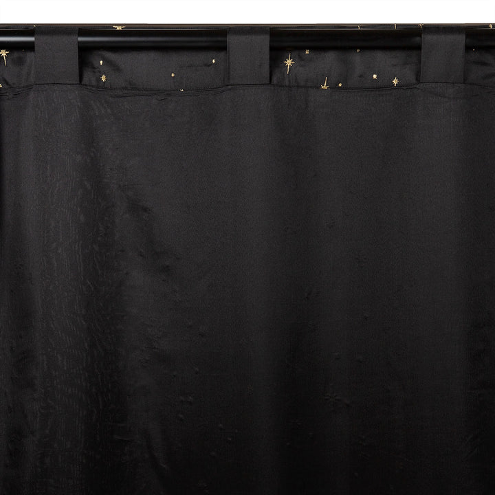 Back of a black semi-sheer curtain with embroidered gold star pattern