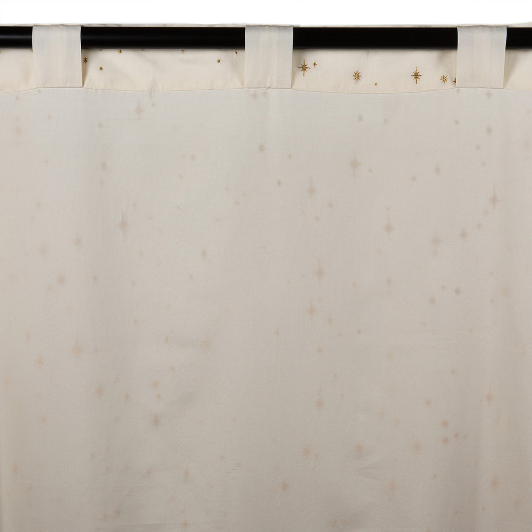 Back of an ivory semi-sheer curtain with embroidered gold star pattern