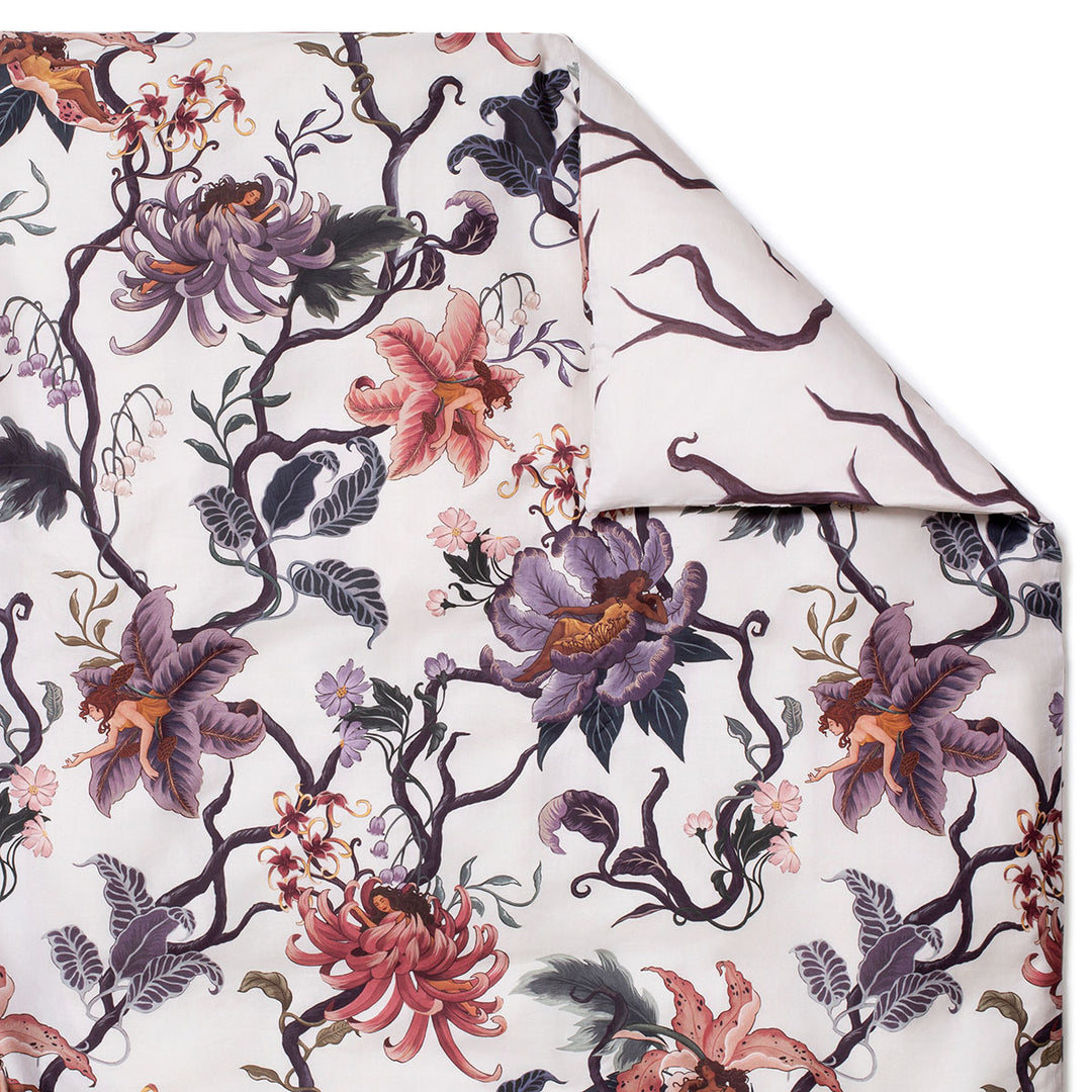 Romantic floral bedding by Sin in Linen. Nymphs bloom out of flowers on a light background on this fairy inspired duvet cover. Hues of lilac and rose abound on this reversible bedding.