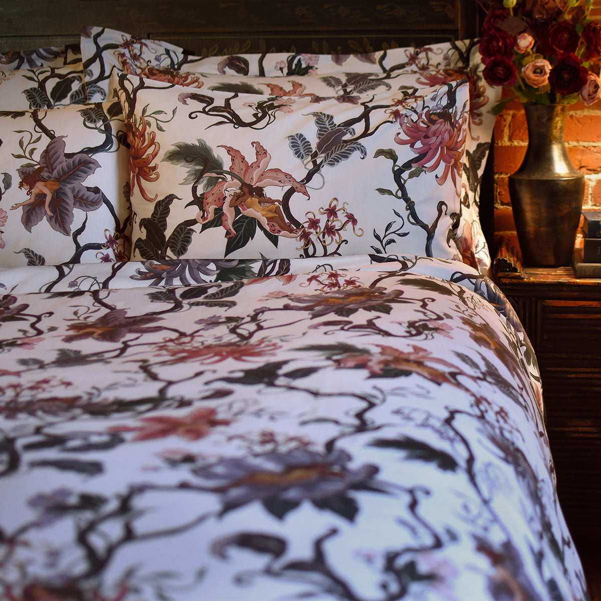 Romantic floral bedding by Sin in Linen. Nymphs bloom out of flowers on a light background in this fairy inspired bedding collection. Hues of lilac and rose abound. 