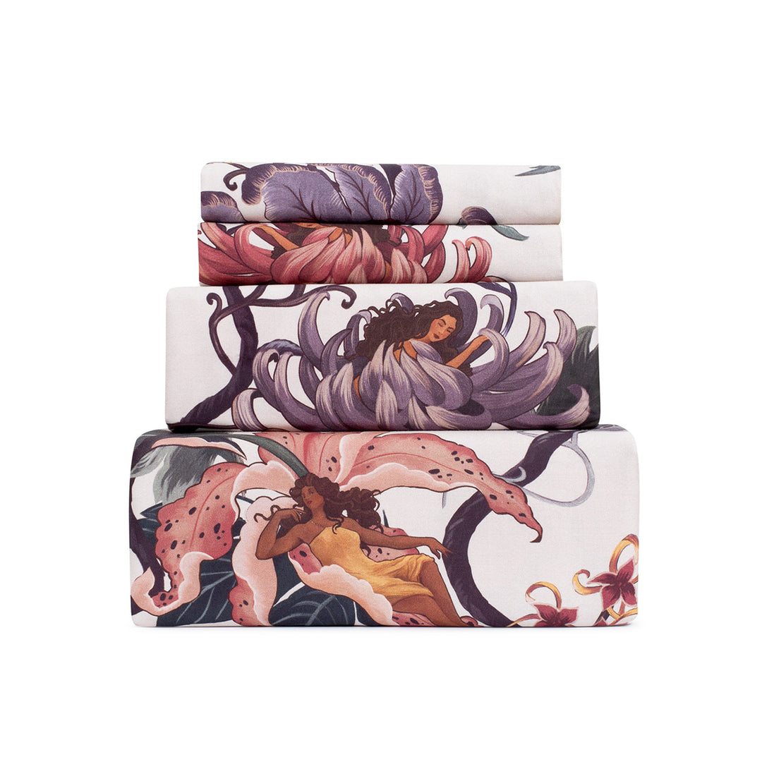Romantic floral bedding by Sin in Linen. Nymphs bloom out of flowers on a light background in this fairy inspired sheet set. Hues of lilac and rose abound. 