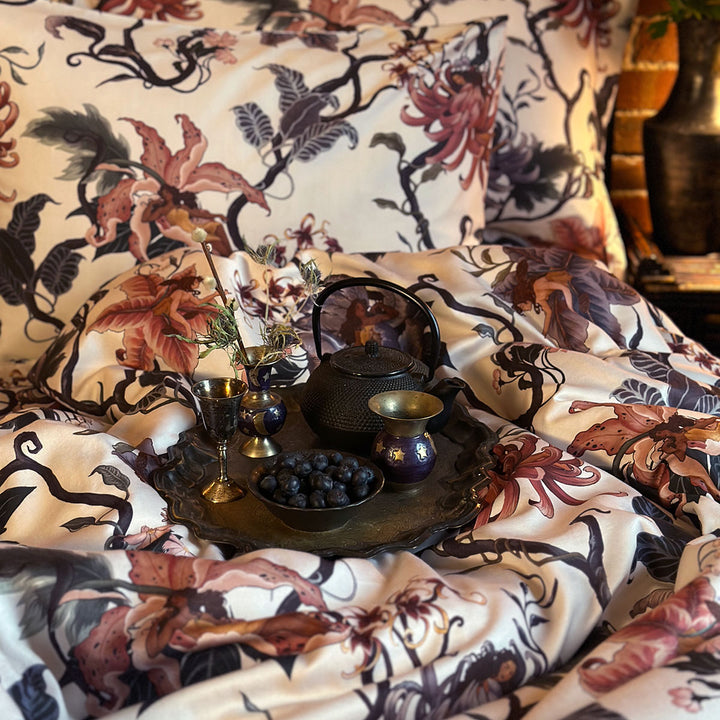 Romantic floral bedding by Sin in Linen. Nymphs bloom out of flowers on a light background in this fairy inspired bedding collection. Hues of lilac and rose abound. 