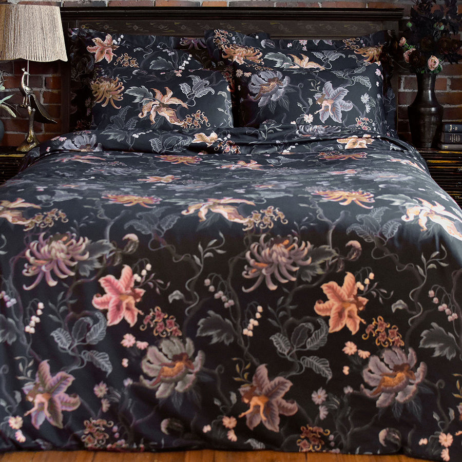 Romantic floral bedding by Sin in Linen. Nymphs bloom out of flowers on a dark background in this fairy inspired bedding collection. Hues of lilac and rose abound. 