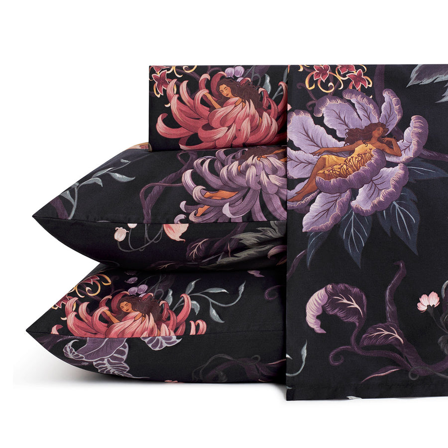 Romantic floral bedding by Sin in Linen. Nymphs bloom out of flowers on a dark background on these fairy inspired sheets. Hues of lilac and rose abound. 