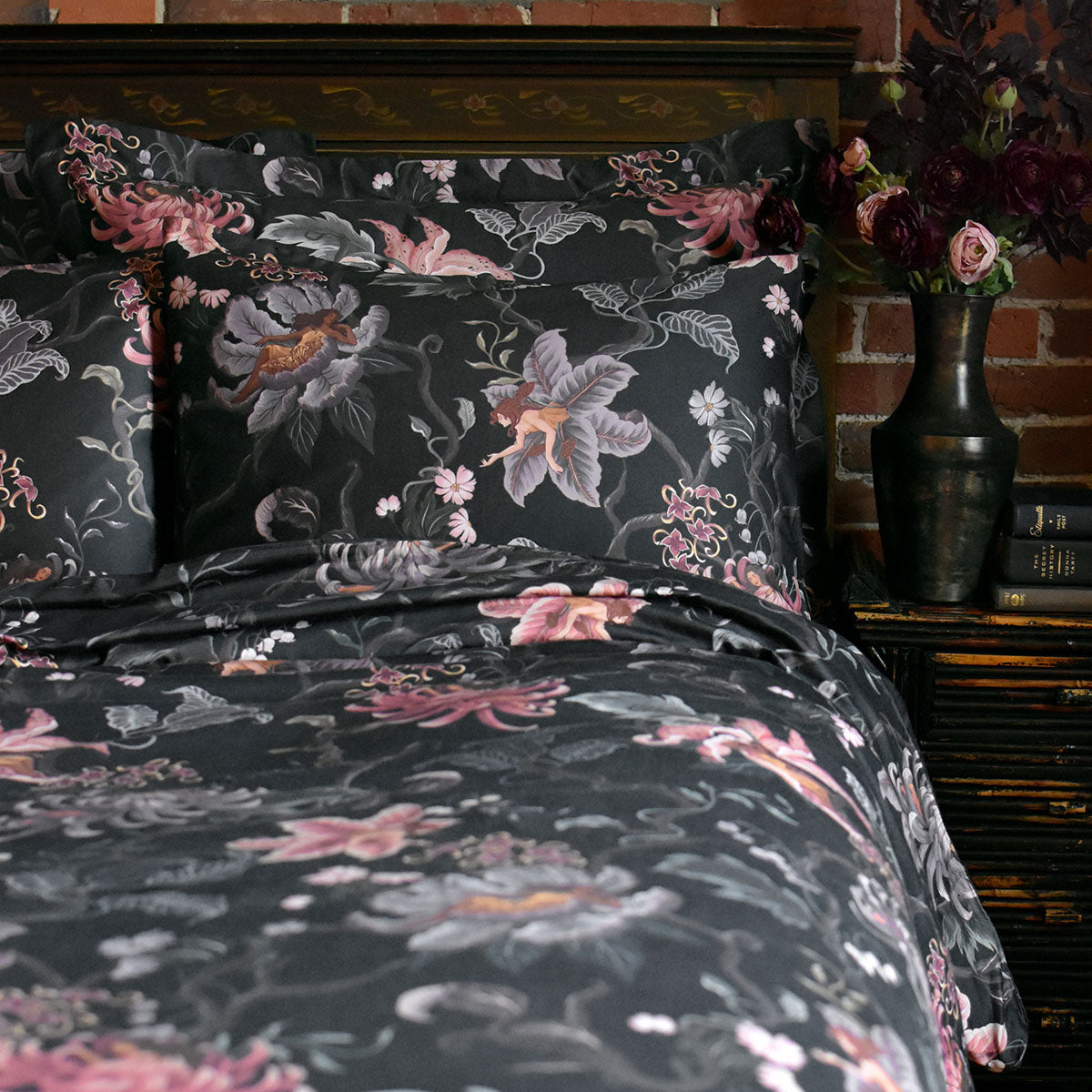 Romantic floral bedding by Sin in Linen. Nymphs bloom out of flowers on a dark background in this fairy inspired bedding collection. Hues of lilac and rose abound. 