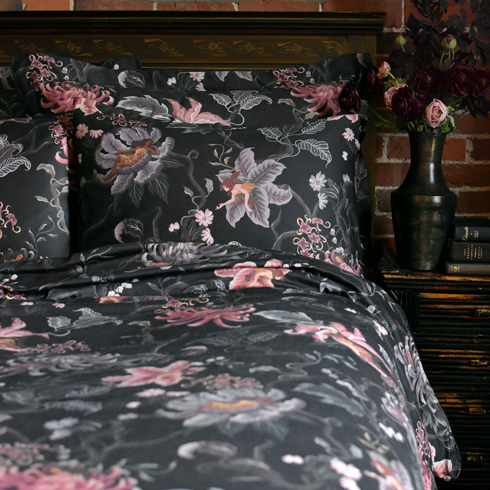 Romantic floral bedding by Sin in Linen. Nymphs bloom out of flowers on a dark background in this fairy inspired bedding collection. Hues of lilac and rose abound. 