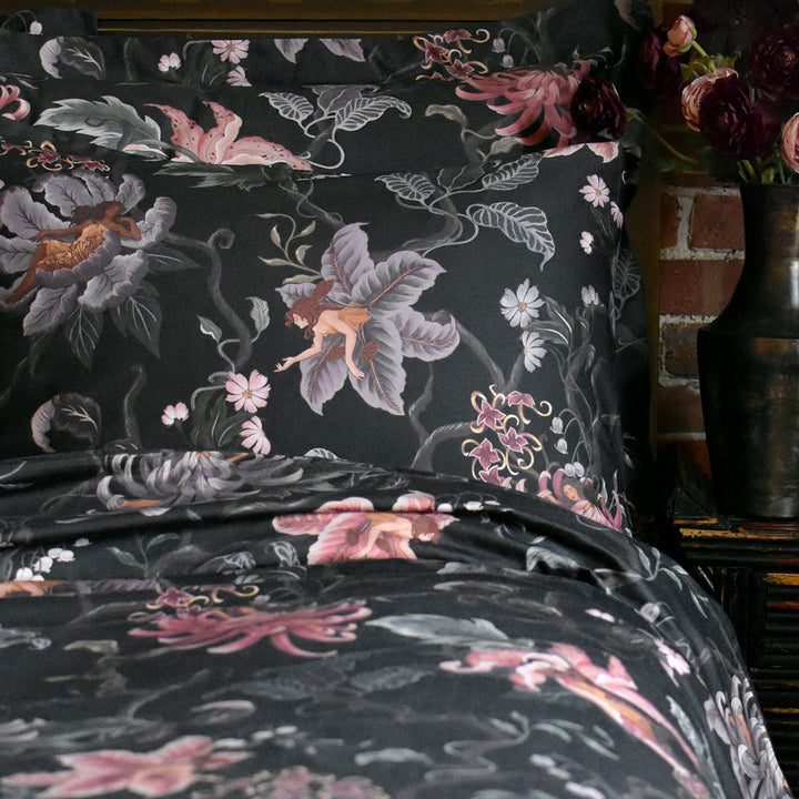 Romantic floral bedding by Sin in Linen. Nymphs bloom out of flowers on a dark background in this fairy inspired bedding collection. Hues of lilac and rose abound. 