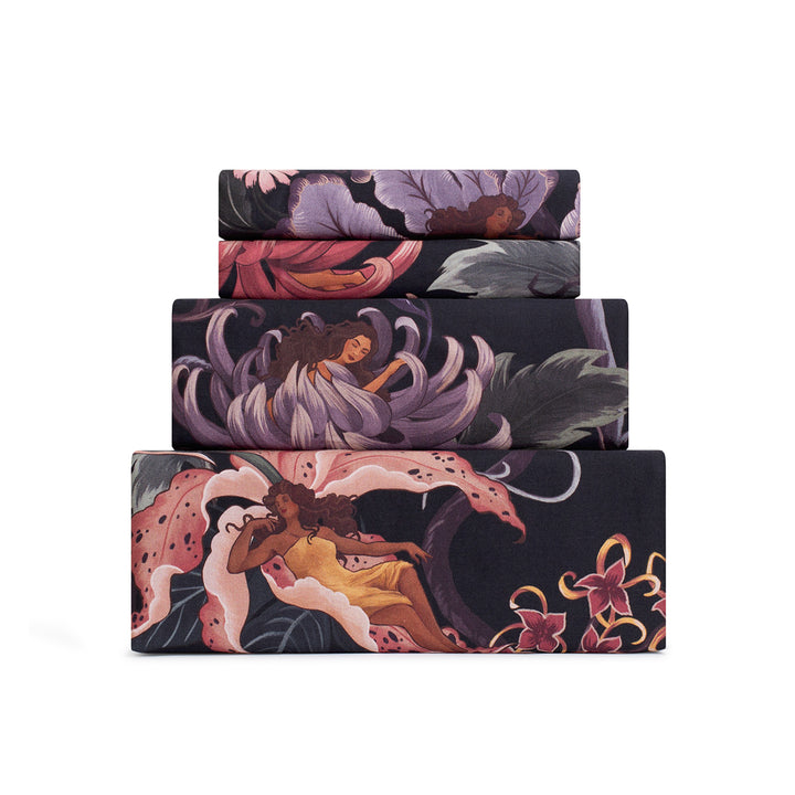 Romantic floral bedding by Sin in Linen. Nymphs bloom out of flowers on a dark background on these fairy inspired sheets. Hues of lilac and rose abound. 