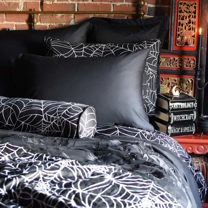 Black Bamboo Pillowcases and Spider web patterned bedding set on a bed with a dark and eerie atmosphere.