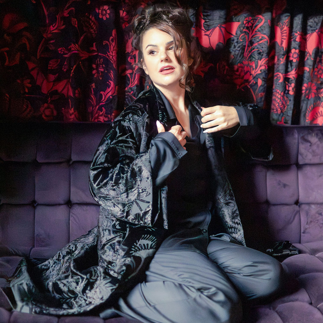 Woman wearing black velvet robe with bats and venus fly traps and black bamboo pajamas.