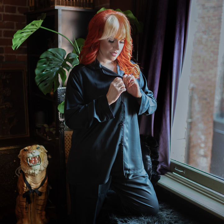 Woman wearing black bamboo pajamas next to a window.