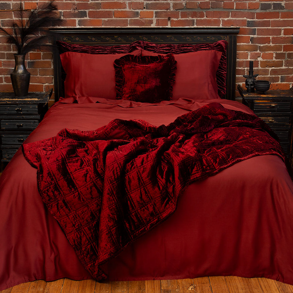 Oxblood Burgundy red bamboo bedding on a whole bed with ruby red velvet accent pillows and box quilt. 