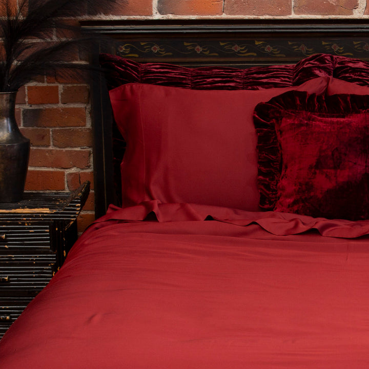 Oxblood burgundy red bamboo pillowcases on a bed with velvet accent pillows. Gothic bedding. 
