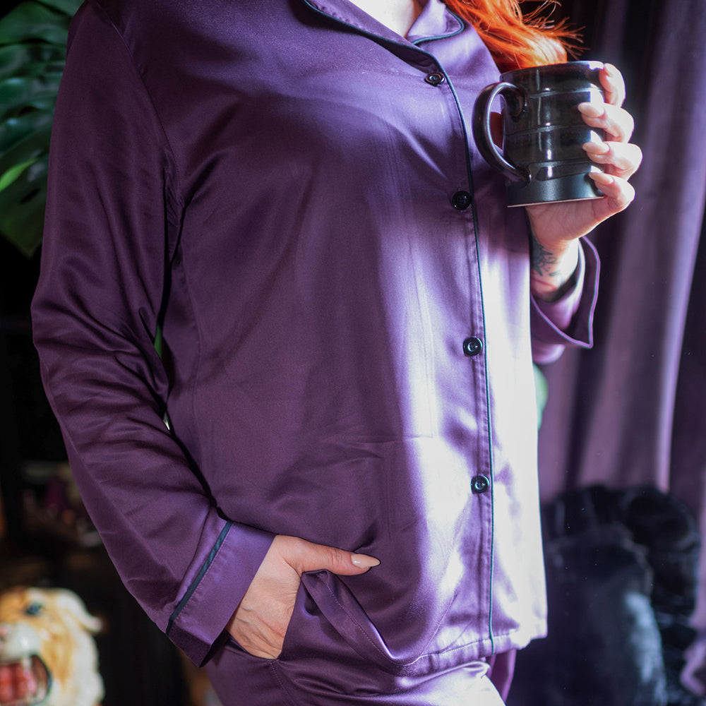 Woman wearing purple bamboo pajamas with her hand in her pocket showing the detailed black piping and black buttons.