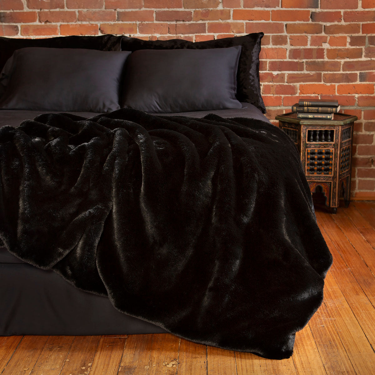 Black faux fur blanket draped over a bed. Gothic and cozy decor. 