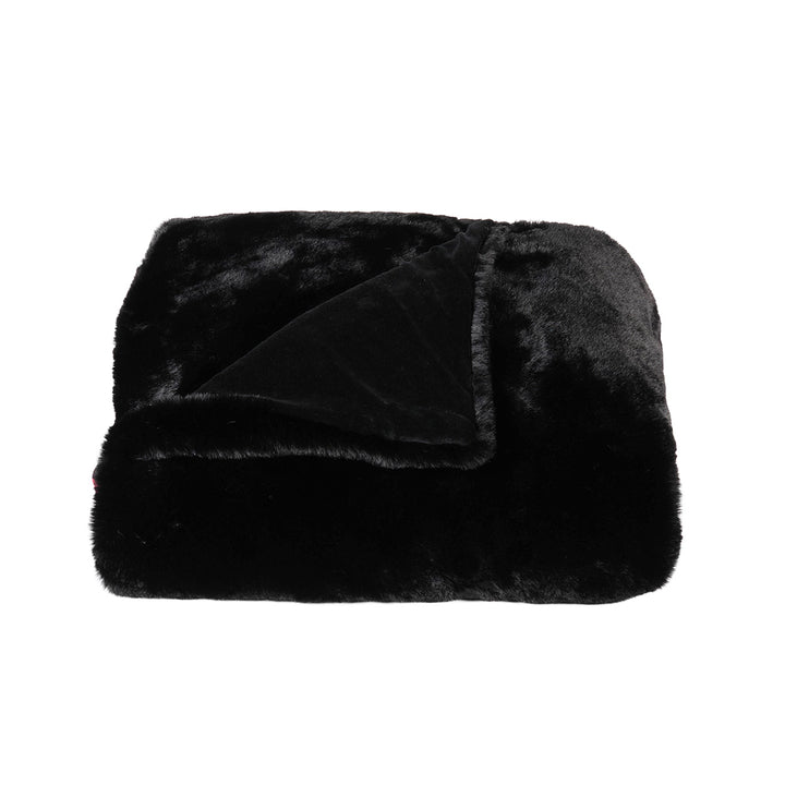 Black faux fur blanket on a white background. Gothic and cozy decor. 