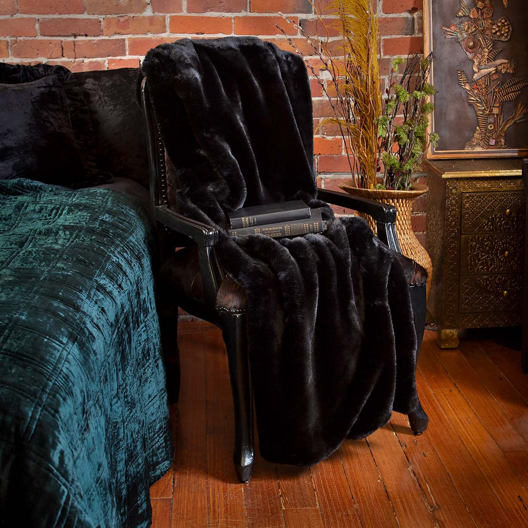 Forest green velvet box quilt on a bed. Featuring also a black faux fur blanket. Dark, moody velvet bedding. 