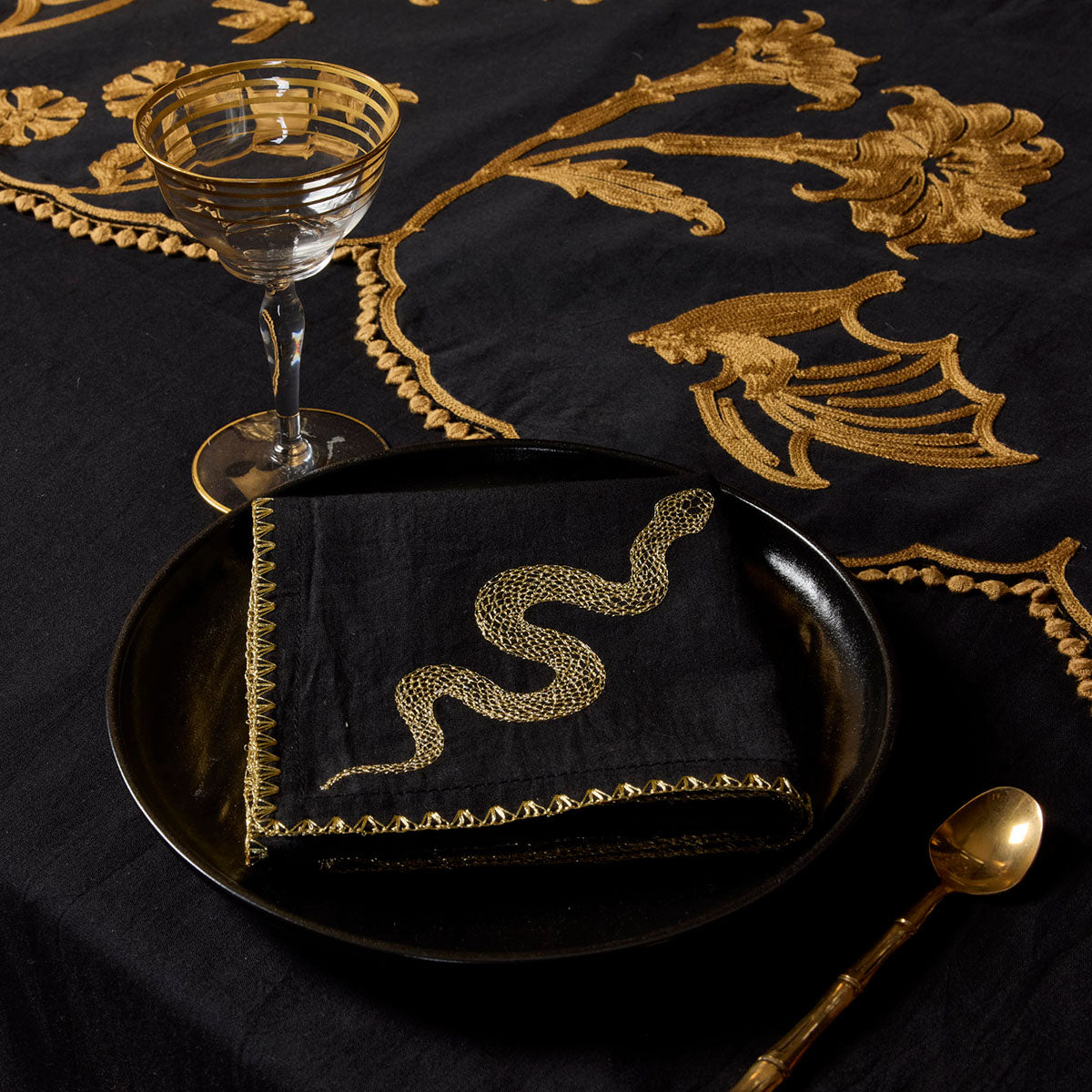 A gold embroidered snake napkin with stitched edges. Witchy, occult inspired table linens by Sin in Linen. 