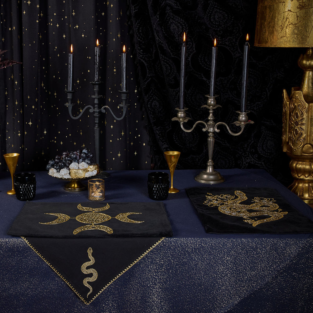 A ritualcore inspired witchy tablescape from Sin in Linen. Navy Lurex Tablecloths with gold glitter sit below beaded altar cloths and embroidered napkins for a gilded feast. 