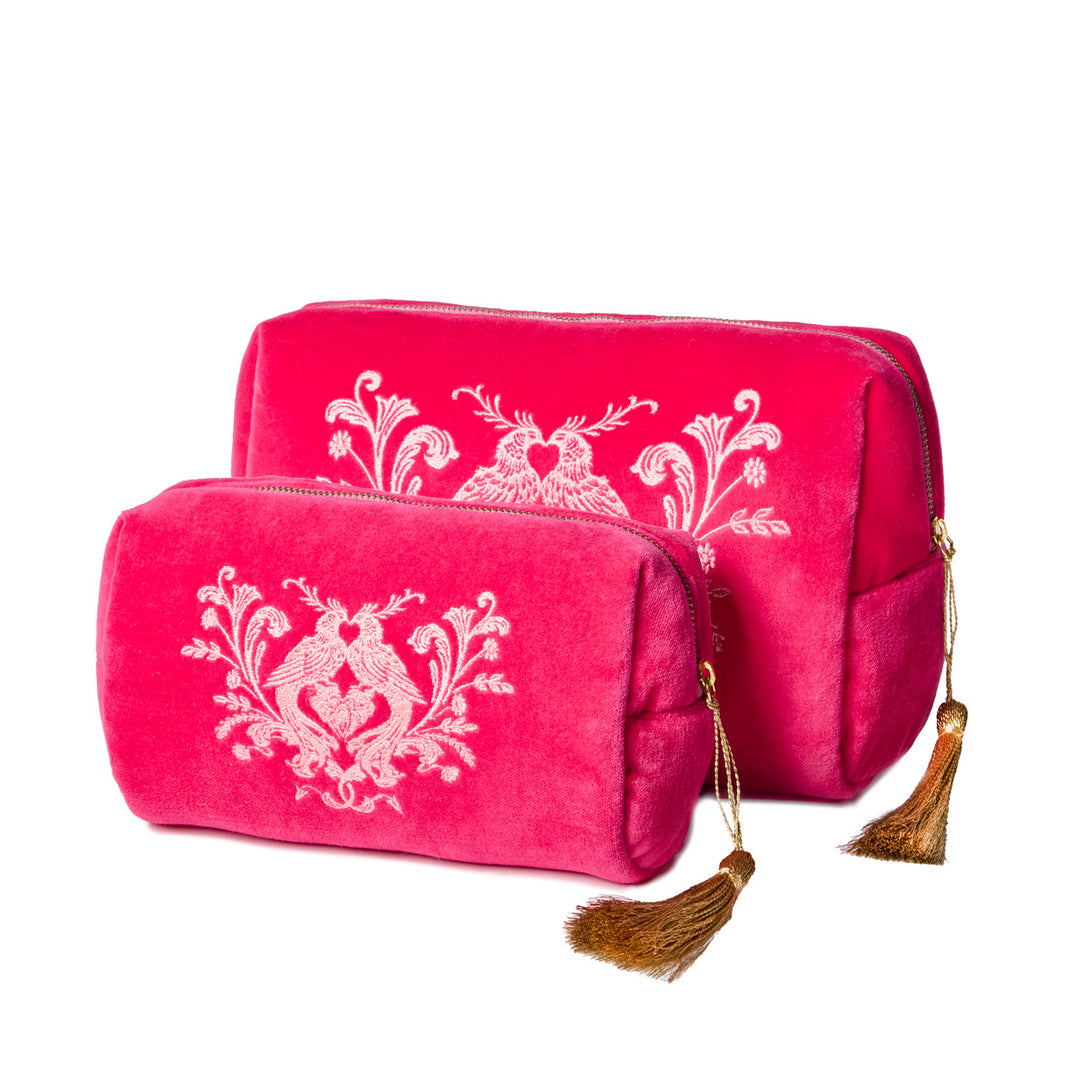Two pink velvet pouches with embroidered love birds and gold tassels on a white background